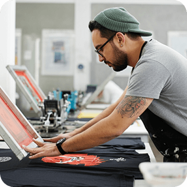 Custom Ink logo over an image of a person screenprinting a t-shirt